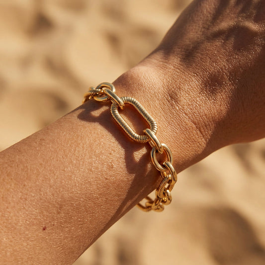 Maglia Gliederarmband aus 14 Karat vergoldetem Edelstahl am Handgelenk bei warmem Sonnenlicht.