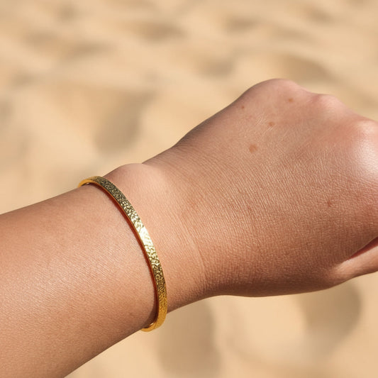 Martella gehämmerter Armreif Gold am Handgelenk getragen, schmaler Armreif aus 18 Karat PVD-vergoldetem Edelstahl.
