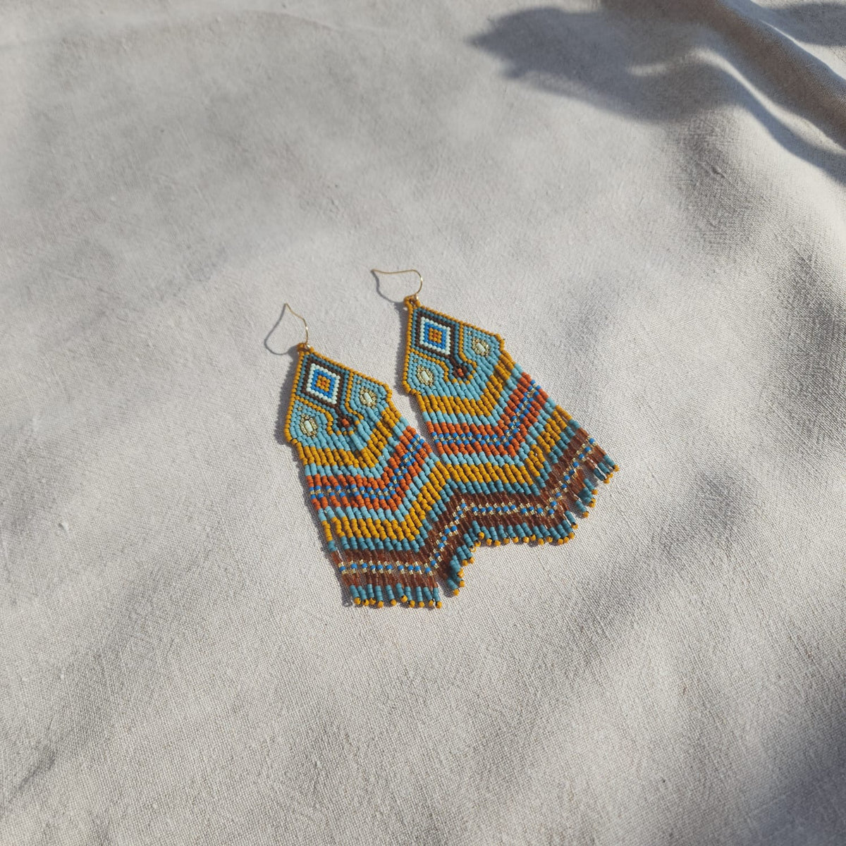 Detailansicht eines Sirocco Blu Miyuki Ohrrings auf Leinen mit geometrischem Delica-Perlenmuster.