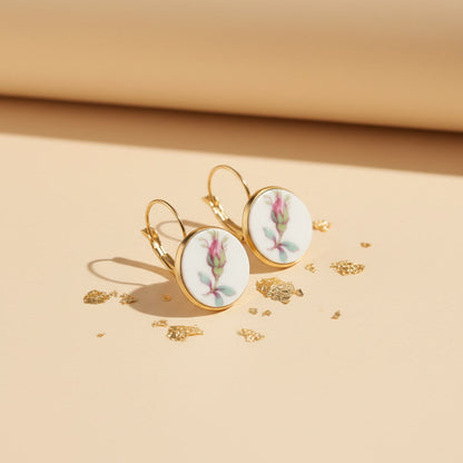 Nahaufnahme der Alba Rosa Ohrringe aus einer seitlichen Perspektive auf einem neutralen Untergrund. Das filigrane florale Motiv der Rose und die hochwertige Verarbeitung der goldfarbenen Klappbrisuren sind deutlich erkennbar und unterstreichen das edle Unikat-Design.
