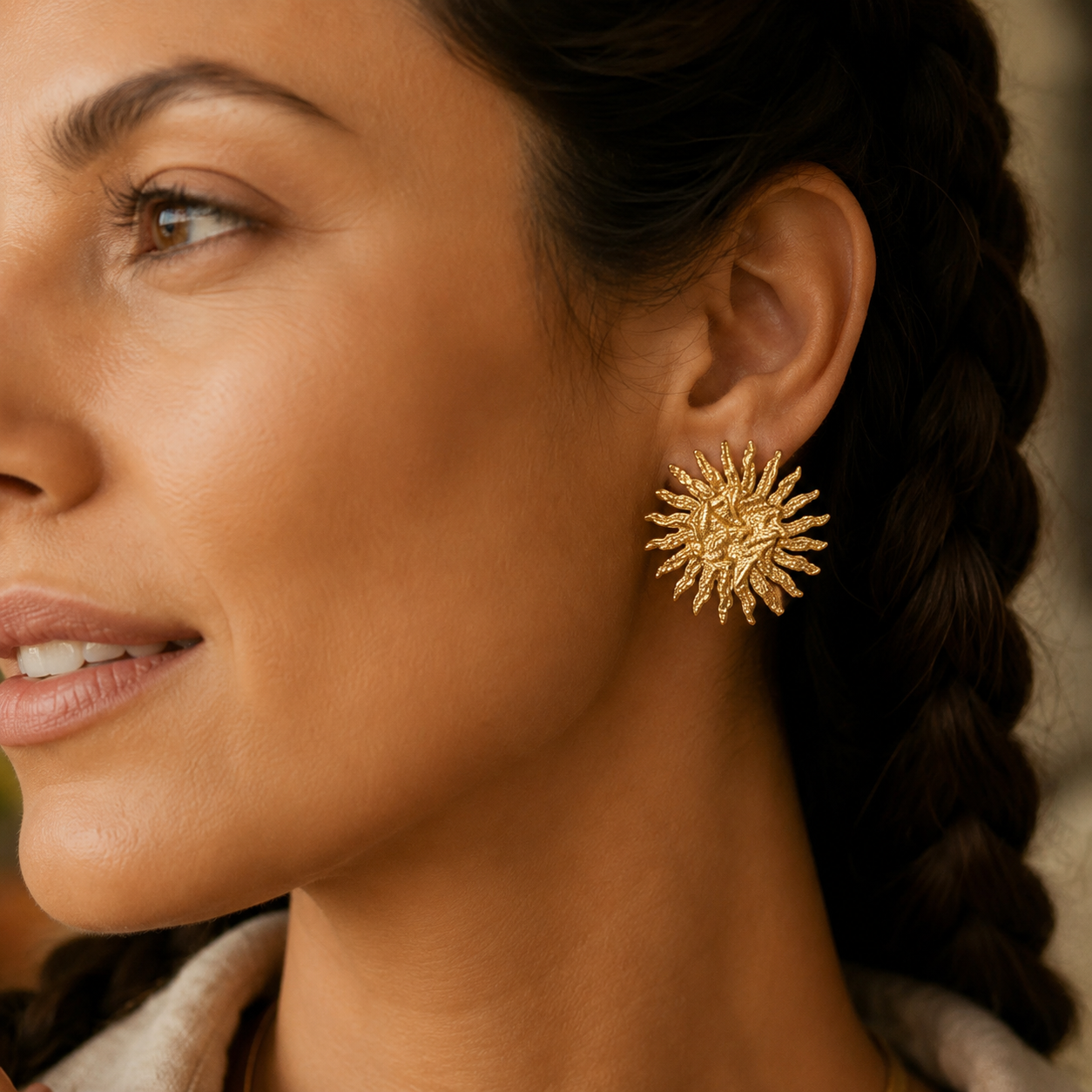 Model trägt Solina Sonnenohrringe in Gold mit gehämmerter Oberfläche.