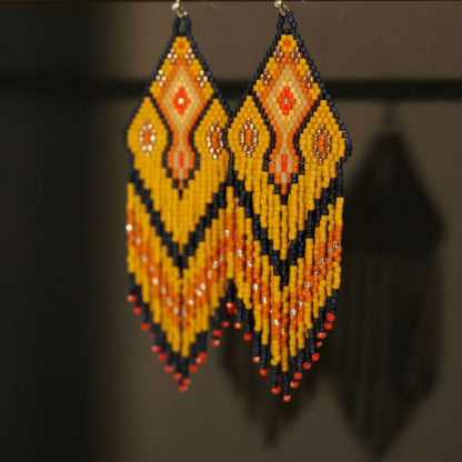 Detaillierte Makroaufnahme des handgewebten Rautenmusters der Ohrringe Sinfonia d’Oro von EDELATELIER. Das präzise geometrische Design aus hochwertigen Miyuki-Perlen vereint tiefschwarze Elemente mit strahlenden Goldakzenten und sanften Beigetönen.