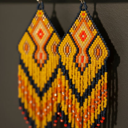 Detaillierte Makroaufnahme des handgewebten Rautenmusters der Ohrringe Sinfonia d’Oro von EDELATELIER. Das präzise geometrische Design aus hochwertigen Miyuki-Perlen vereint tiefschwarze Elemente mit strahlenden Goldakzenten und sanften Beigetönen.