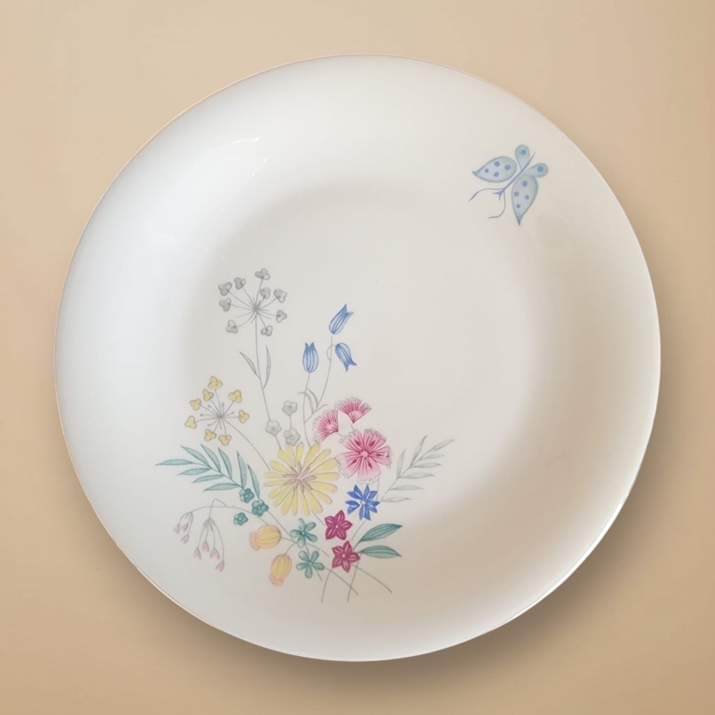 Vorderansicht des antiken Bavaria Porzellantellers mit dem originalen „Cyanus“-Dekor, bestehend aus einem hellblauen Schmetterling und filigranen Frühlingsblumen auf reinweißem Grund.