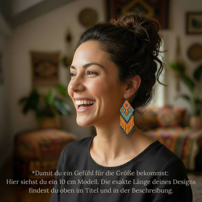 Tragebeispiel von EDELATELIER. zur Größenorientierung: Eine lachende Frau mit Dutt trägt 10 cm lange Perlenohrringe vor einem Boho-Hintergrund. Der Text im Bild erklärt, dass dies der Veranschaulichung dient und die exakte Länge des jeweiligen Designs im Titel und in der Beschreibung zu finden ist.