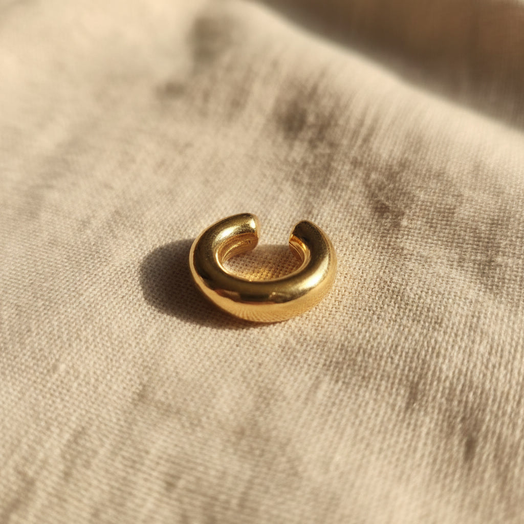Breiter Ear Cuff Anello aus vergoldetem Edelstahl 304 mit 18K Gold PVD-Beschichtung auf naturfarbenem Leinenstoff.