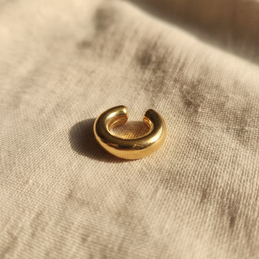 Breiter Ear Cuff Anello aus vergoldetem Edelstahl 304 mit 18K Gold PVD-Beschichtung auf naturfarbenem Leinenstoff.