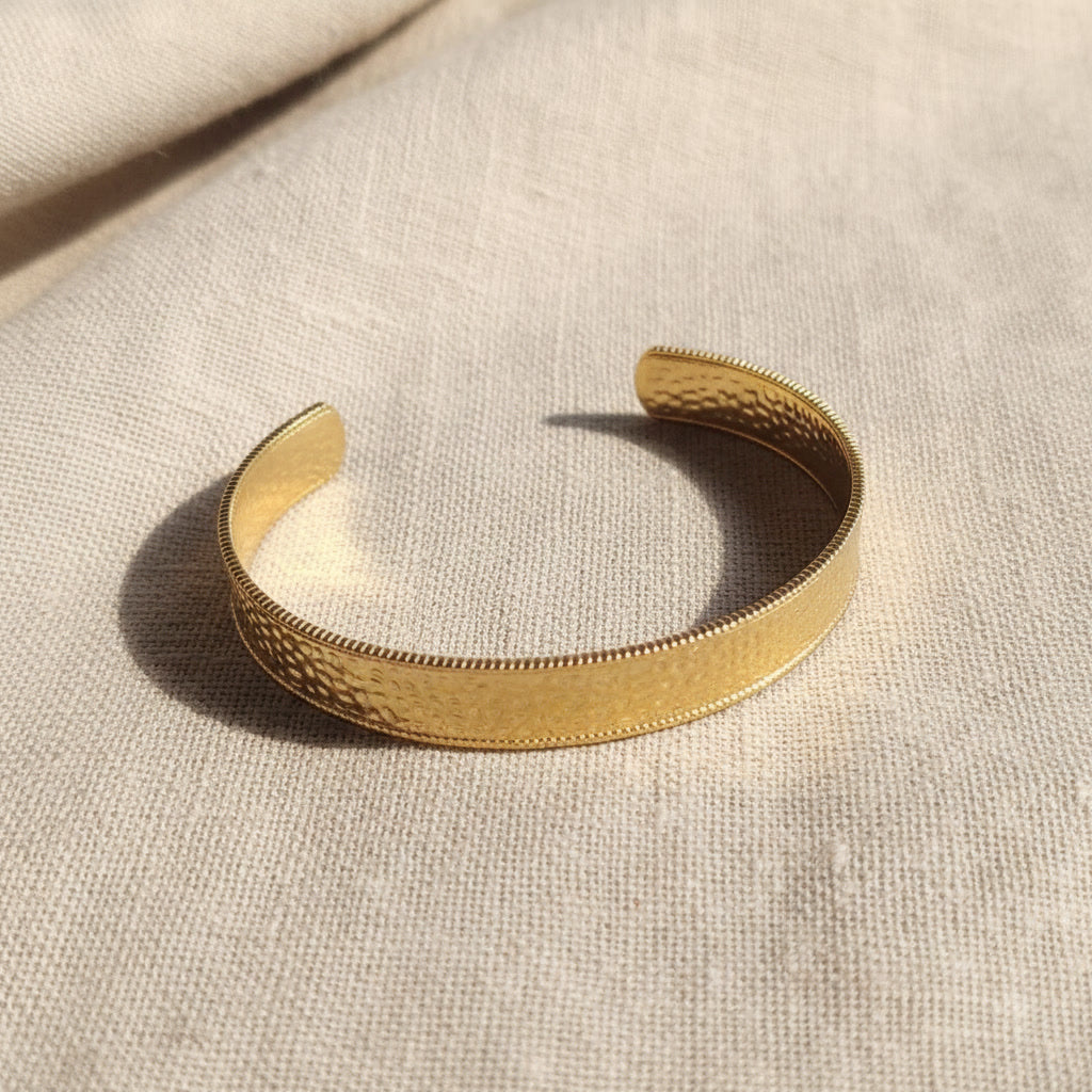 Aurelia Armreif Gold in schräger Ansicht mit gehämmerter Oberfläche und offener Form.