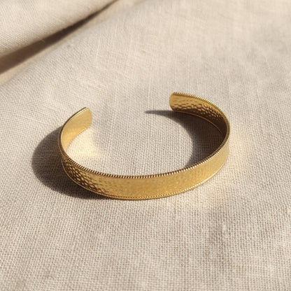 Aurelia Armreif Gold in schräger Ansicht mit gehämmerter Oberfläche und offener Form.