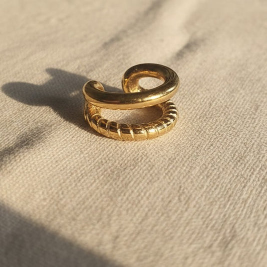 Goldfarbener Ear Cuff Aureus aus Edelstahl mit 18K PVD-Vergoldung auf beigem Leinenstoff – zweireihiges Design mit glatter und strukturierter Oberfläche.