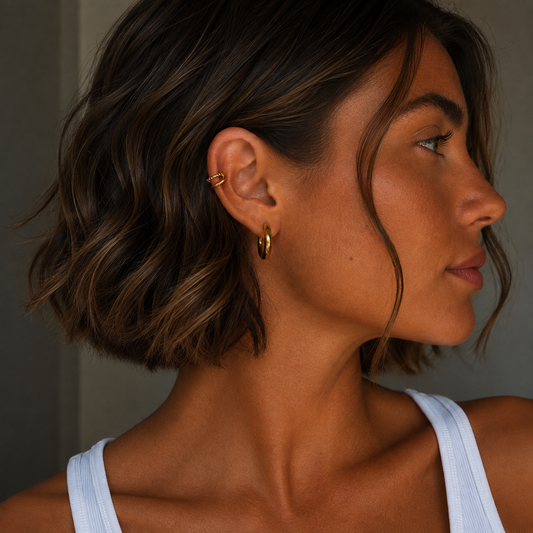Frau mit goldfarbenem Ear Cuff Aureus aus Edelstahl mit 18K PVD-Vergoldung am Ohr getragen – moderner zweireihiger Ear Cuff ohne Ohrloch.