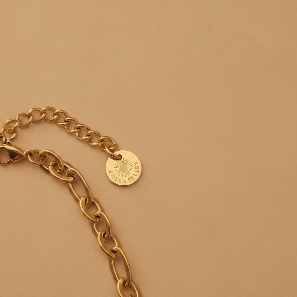 Detailaufnahme der Catena Halskette in Goldfarben mit Karabinerverschluss, Verlängerungskette und EDELATELIER.-Logoplättchen.
