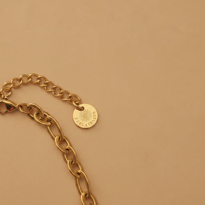 Detailaufnahme der Catena Halskette in Goldfarben mit Karabinerverschluss, Verlängerungskette und EDELATELIER.-Logoplättchen.