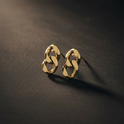Catena Ohrstecker in Gold auf dunklem strukturiertem Hintergrund mit warmem Licht.
