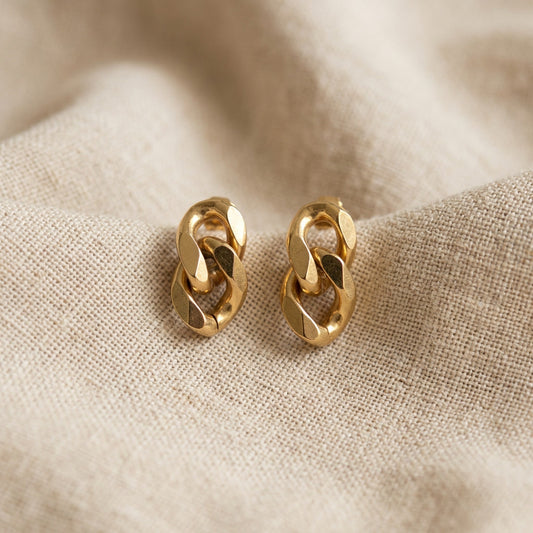 Catena Ohrstecker goldfarben aus Edelstahl mit Kettenglied-Design auf hellem Leinenstoff