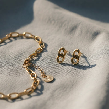 Goldene Catena Ohrstecker mit passendem Armband auf hellem Jeansstoff.