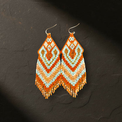 Detaillierte Makroaufnahme der oberen Webstruktur der Statement-Ohrringe Celeste Mattone von EDELATELIER. Das präzise geometrische Rautenmuster aus hellblauen, terrakottafarbenen und goldenen Miyuki-Perlen wird durch die Tiefenschärfe auf dem dunklen Schieferhintergrund besonders hervorgehoben.