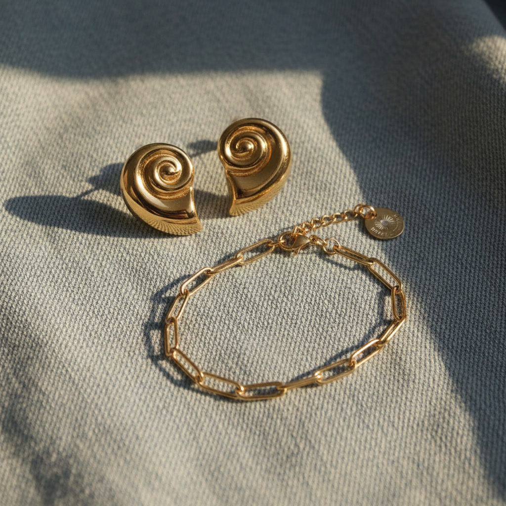 Conchiglia Muschel-Ohrringe in Goldoptik kombiniert mit goldenem Armband.