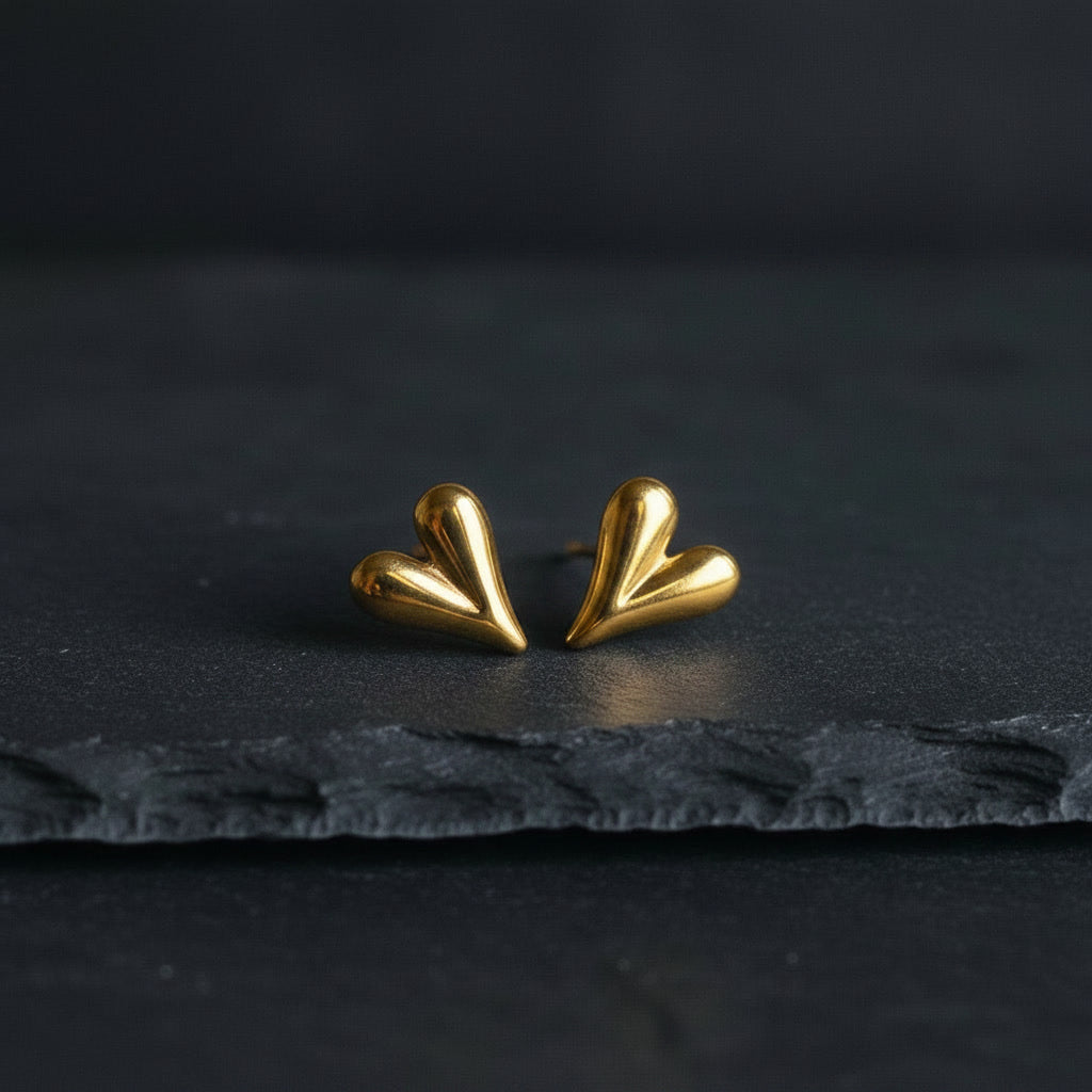 Cuore Piccolo Herzohrringe in Gold auf dunklem Schiefer.