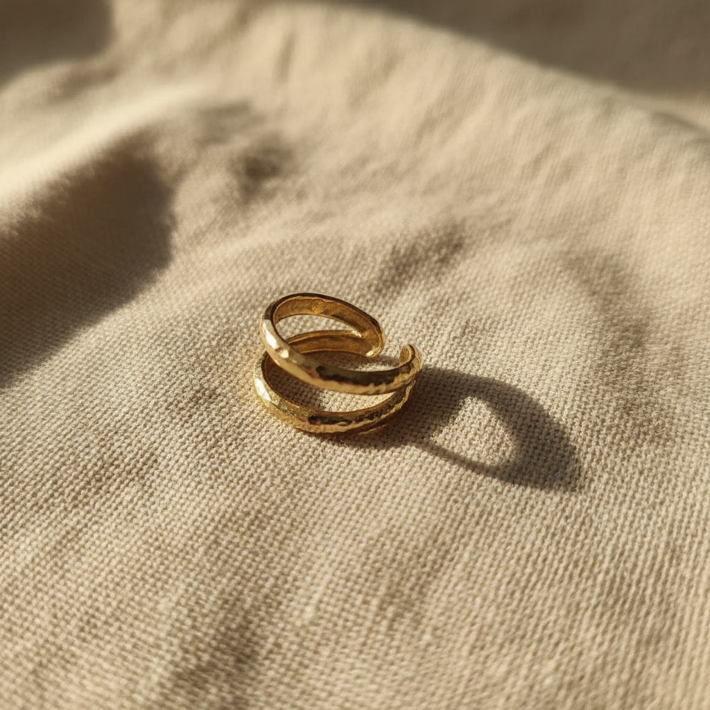 Offener zweireihiger Ear Cuff Martellato in 14K Gold auf hellem Leinen.