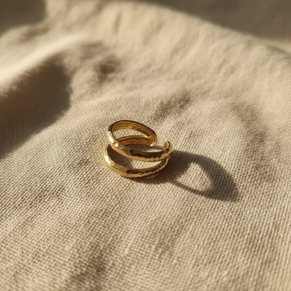 Offener zweireihiger Ear Cuff Martellato in 14K Gold auf hellem Leinen.