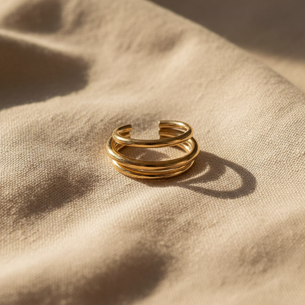 Goldener Ear Cuff Vela aus 304 Edelstahl mit 18K Gold PVD-Beschichtung auf beigem Leinen, Seitenansicht.