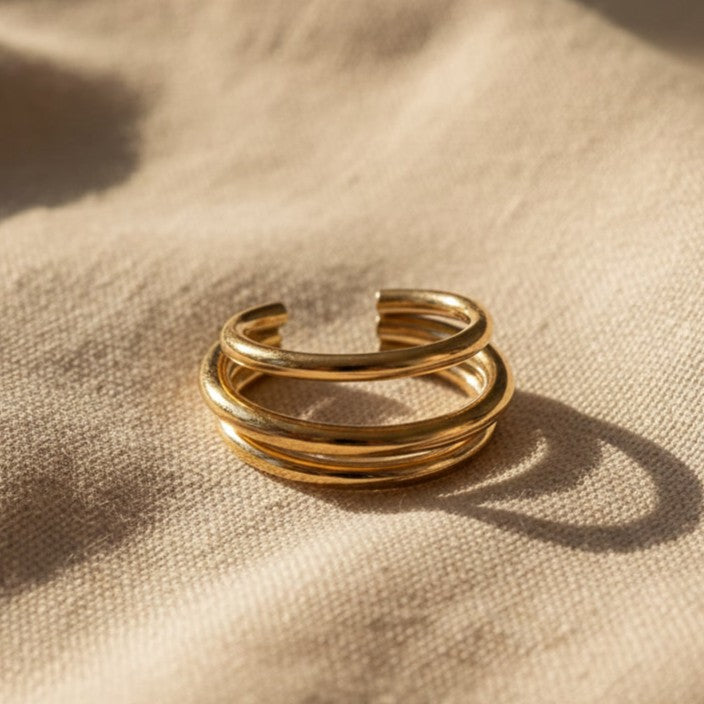 Goldener Ear Cuff Vela aus 304 Edelstahl mit 18K Gold PVD-Beschichtung auf beigem Leinen, Vorderansicht.