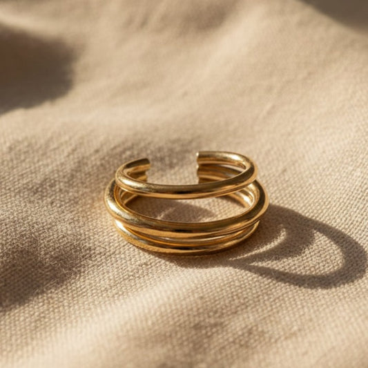 Goldener Ear Cuff Vela aus 304 Edelstahl mit 18K Gold PVD-Beschichtung auf beigem Leinen, Vorderansicht.