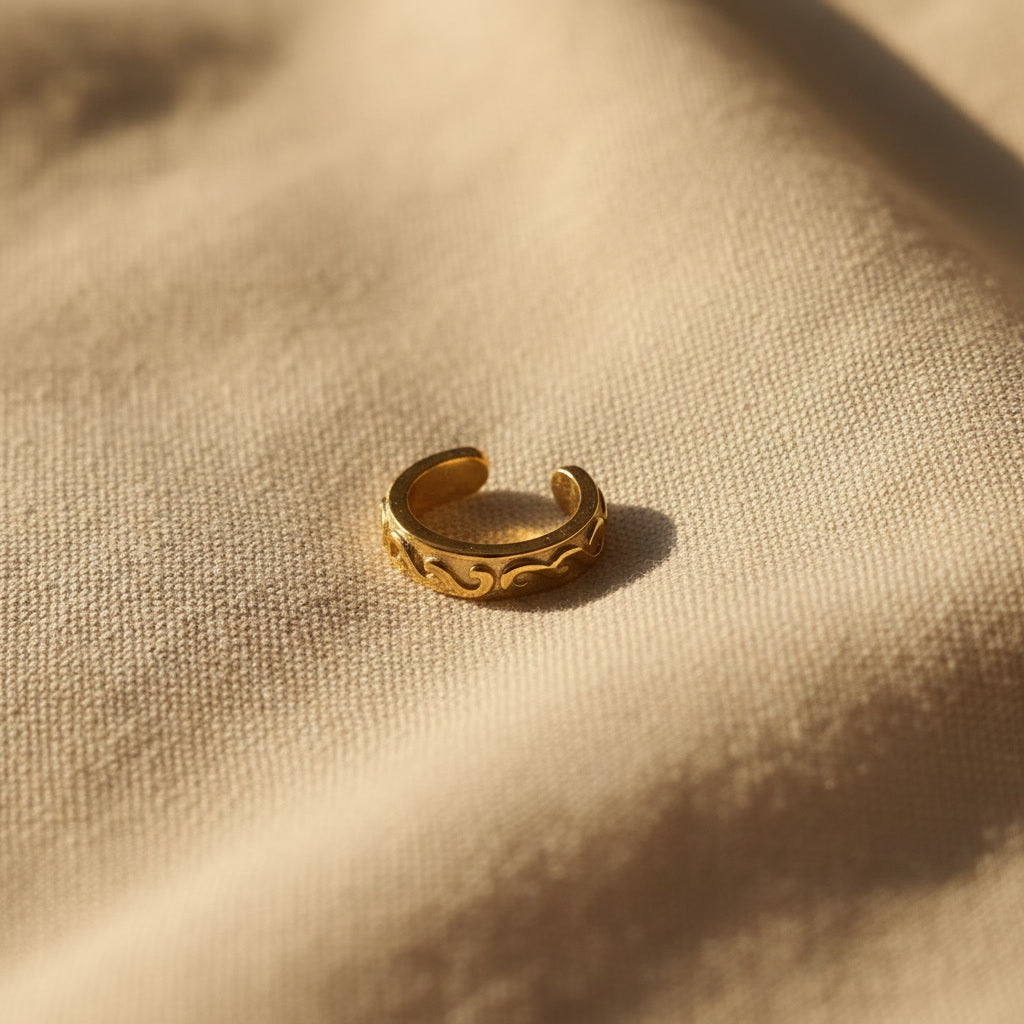 Offener Arabesco Ear Cuff in Gold mit feinem Reliefmuster und sichtbarer Ohrklemmen-Form.