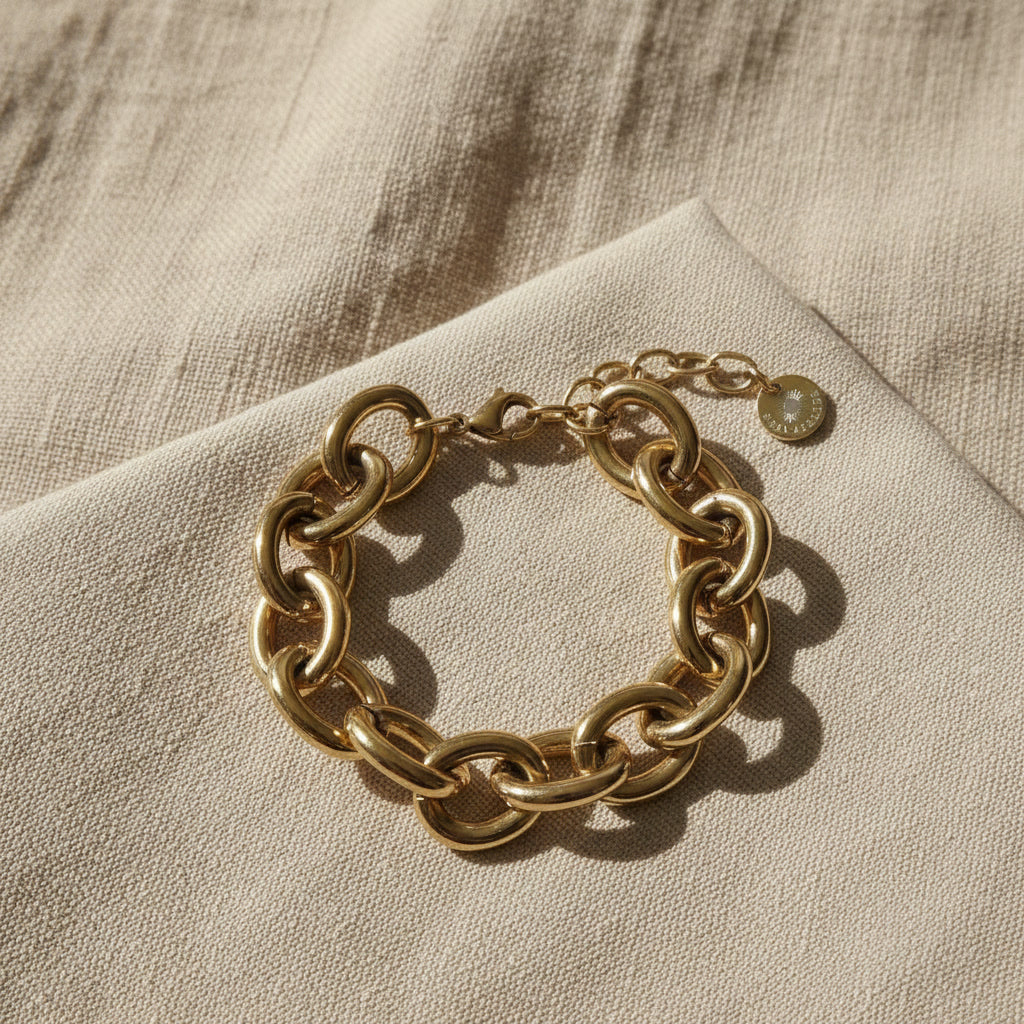Goldfarbenes Bella Chunky Armband auf beigem Leinenstoff im warmen Sonnenlicht.