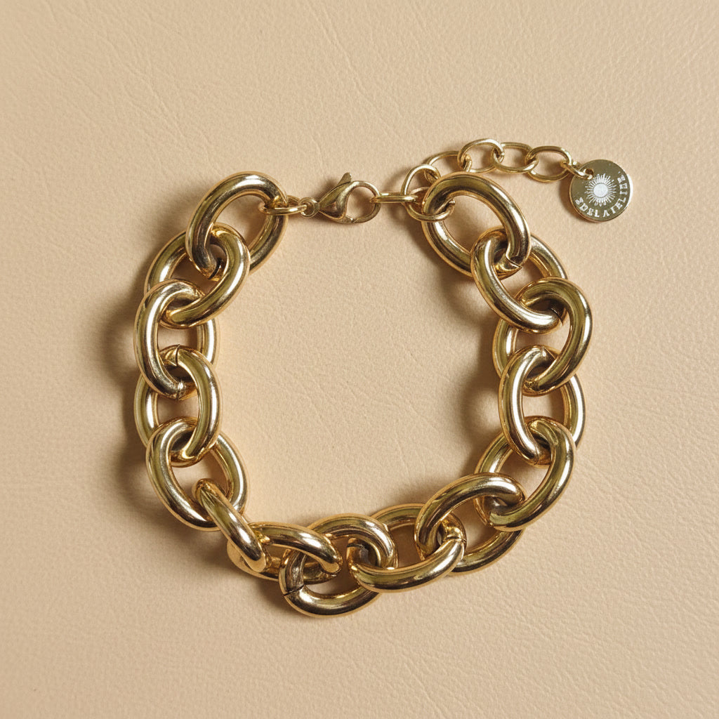 Goldfarbenes Bella Chunky Armband mit großen glänzenden Gliedern auf warmem beigem Hintergrund.