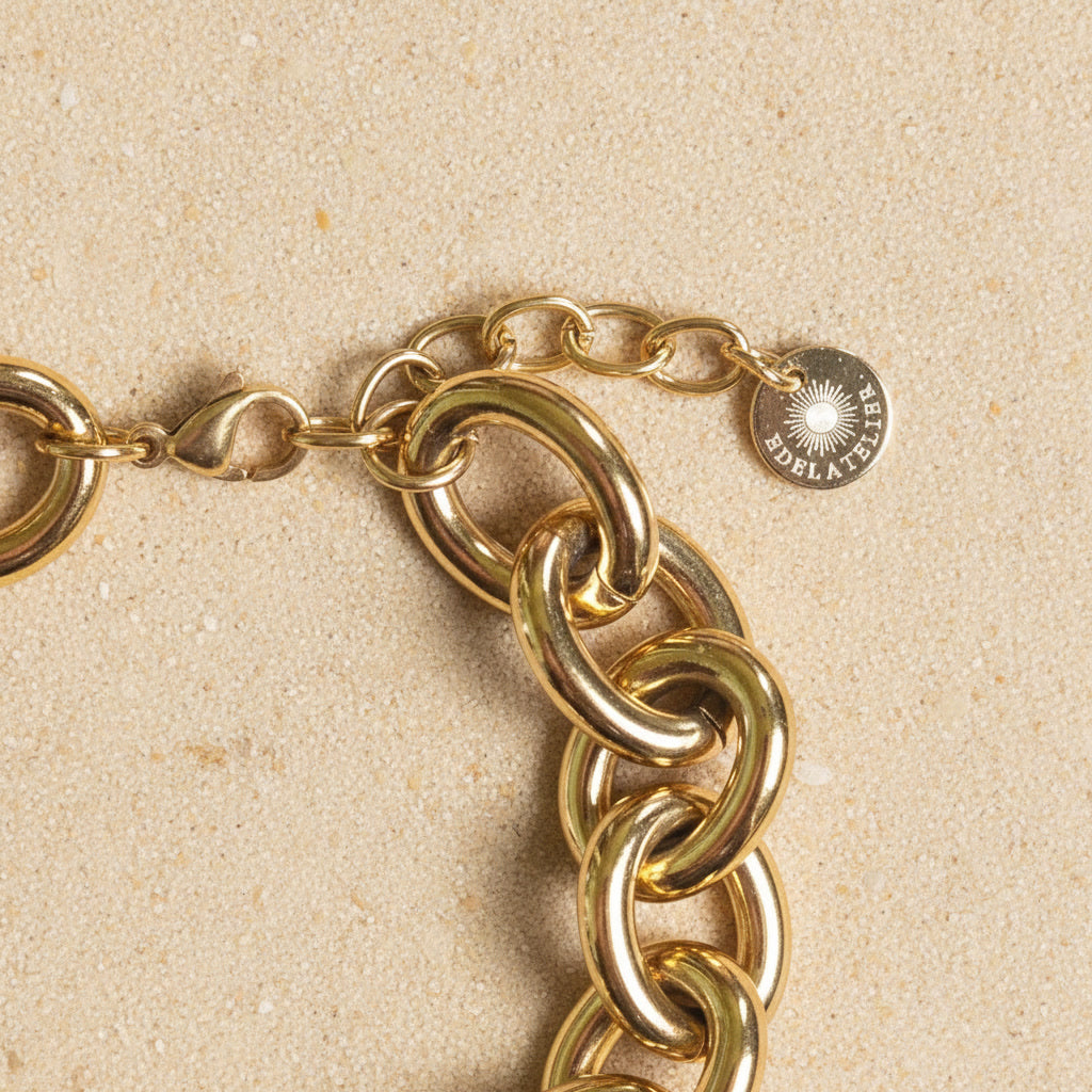 Detailaufnahme des goldfarbenen Bella Chunky Armbands mit Karabiner, Verlängerungskette und EDELATELIER.-Logoplättchen.