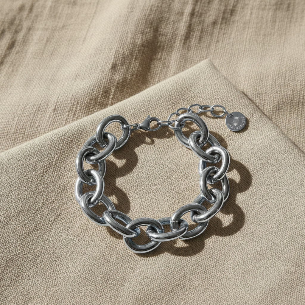 Silberfarbenes Bella Chunky Armband auf beigem Leinenstoff im warmen Sonnenlicht.