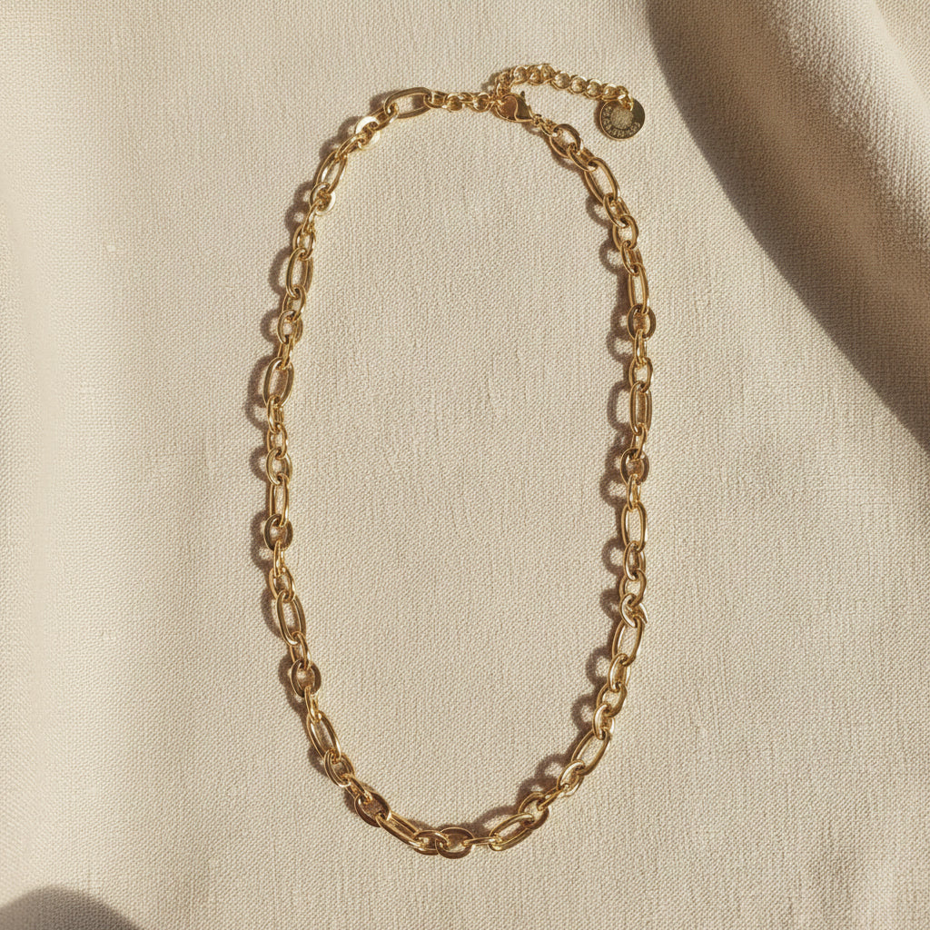 Catena Halskette aus 18 Karat vergoldetem Edelstahl mit ovalen Gliedern auf hellem Leinenstoff.