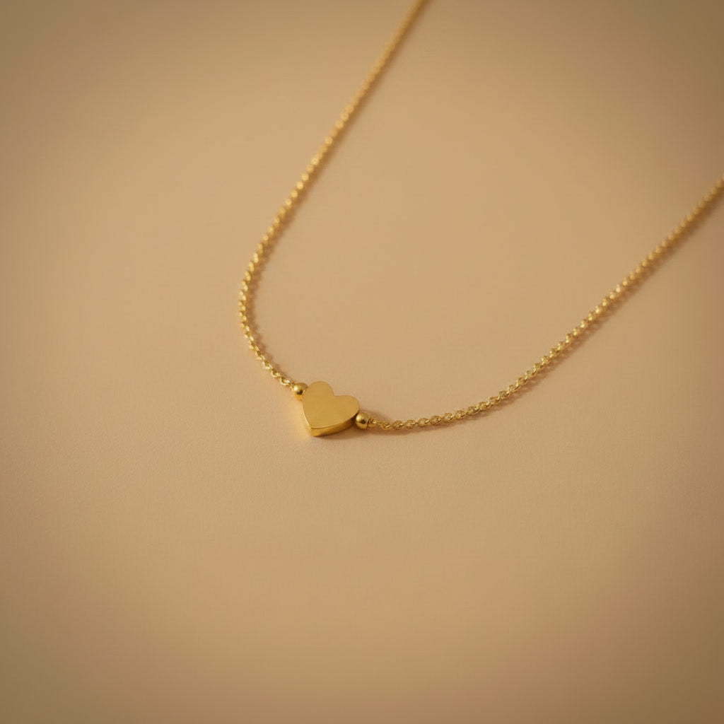 Detailaufnahme der silberfarbenen Cuore Halskette mit kleinem Herzanhänger auf warmem beigem Hintergrund.