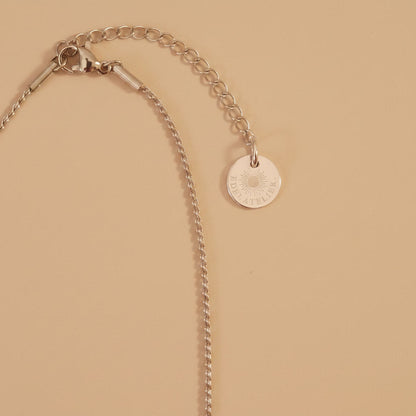 Detailaufnahme der silberfarbenen Cuore Halskette mit Verlängerungskette und EDELATELIER.-Logoplättchen.