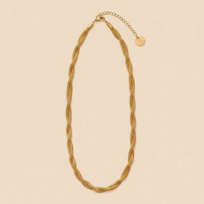 Goldfarbene Intreccia  Halskette mit gedrehter Struktur, Karabiner und Verlängerungskette auf dunklem Hintergrund.
