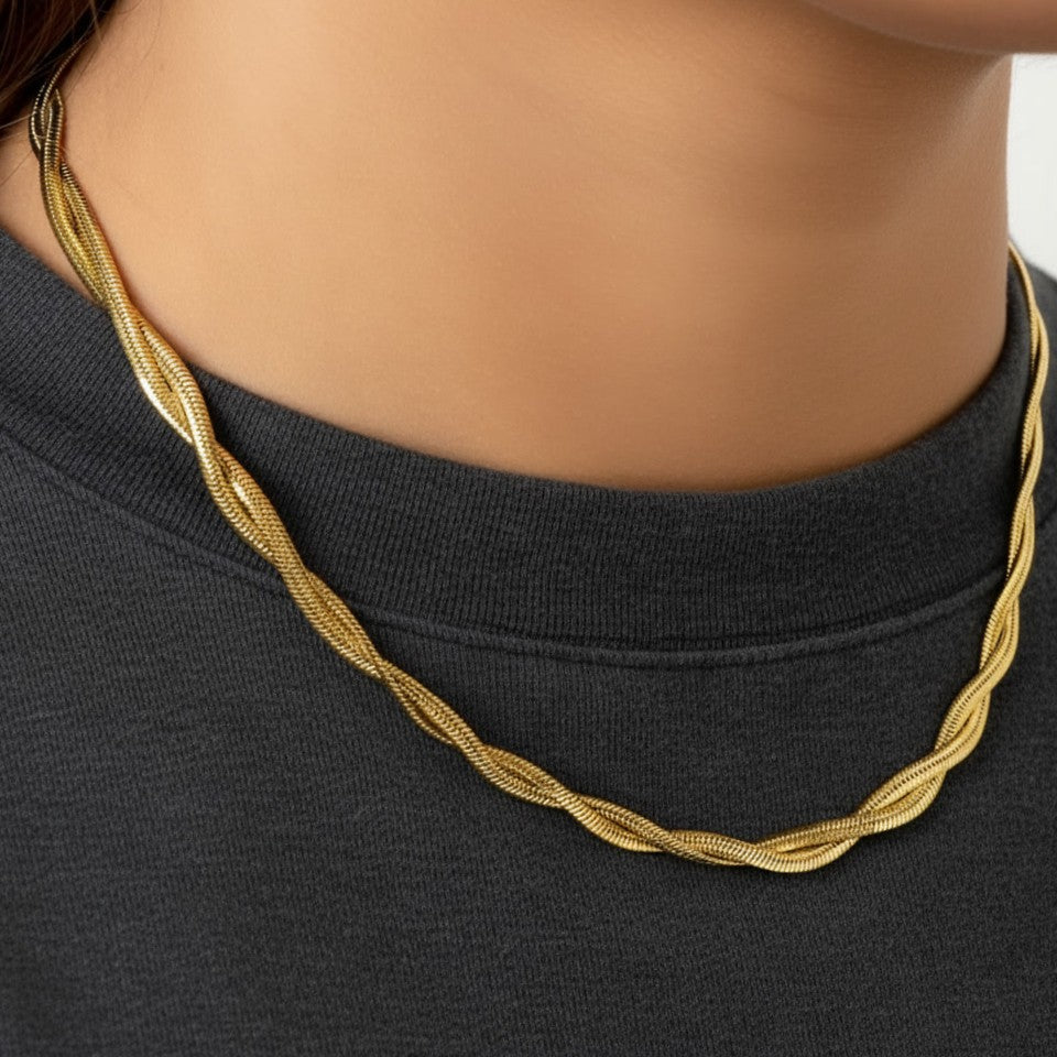 Intreccia Halskette aus 14 Karat vergoldetem Edelstahl als elegante Nahaufnahme am Hals auf dunklem Oberteil.