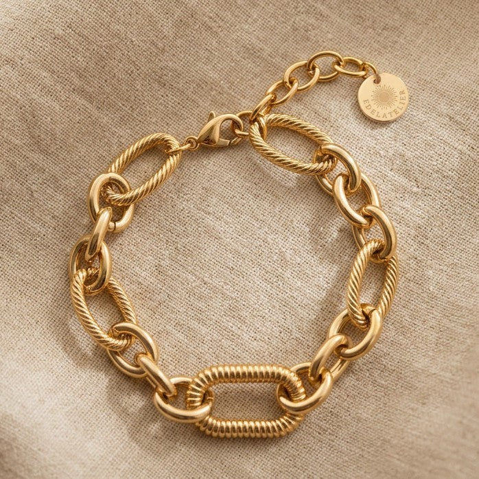 Maglia Gliederarmband aus 14 Karat vergoldetem Edelstahl auf hellem Leinenstoff mit EDELATELIER Logo-Plättchen.