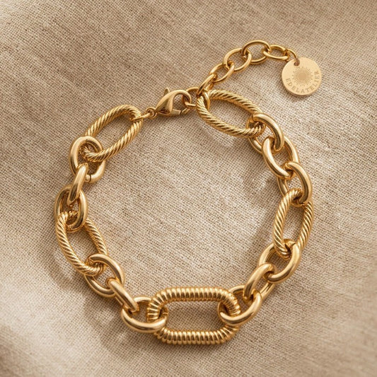 Maglia Gliederarmband aus 14 Karat vergoldetem Edelstahl auf hellem Leinenstoff mit EDELATELIER Logo-Plättchen.