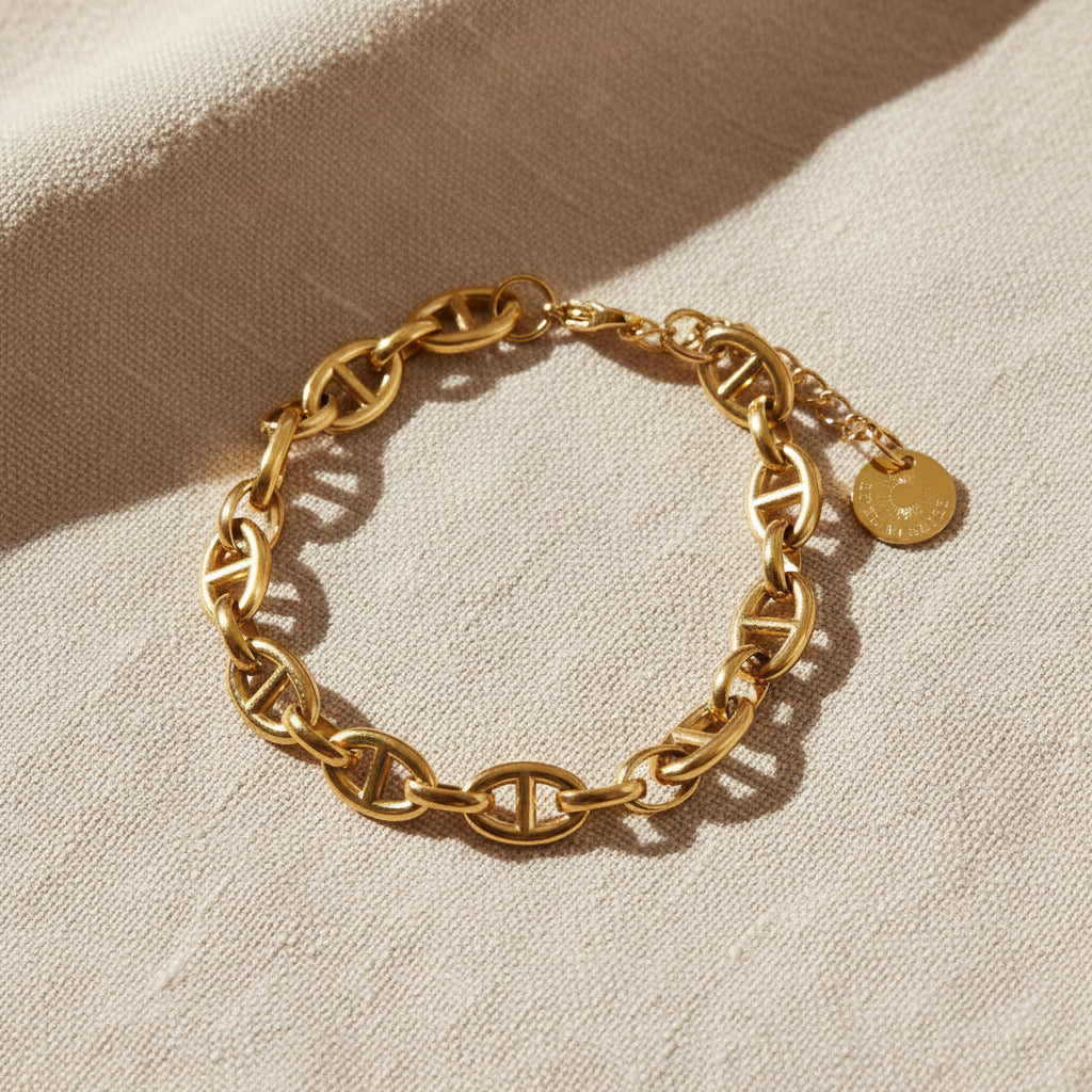 Marea Gliederarmband goldfarben rund ausgelegt auf beigem Leinen, breite Kettenglieder deutlich sichtbar.