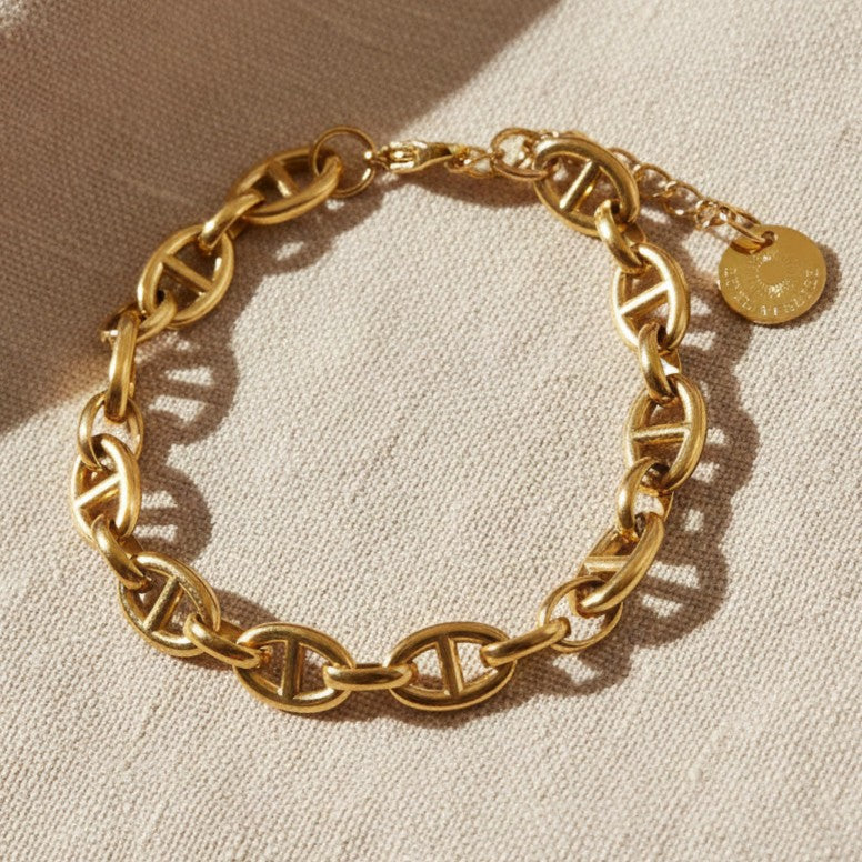 Verschluss und Verlängerungskette des Marea Gliederarmbands aus goldfarbenem Edelstahl auf Leinen.