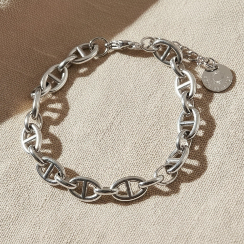 Marea Gliederarmband silberfarben rund ausgelegt auf beigem Leinen, breite Kettenglieder deutlich sichtbar.