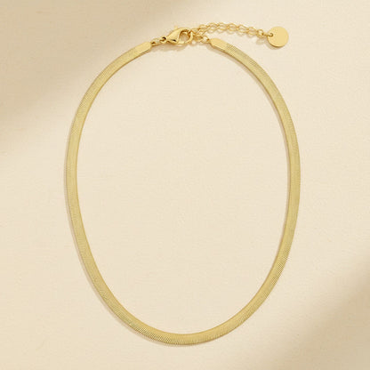 Goldfarbene Serena Halskette mit flacher Struktur, Karabiner und Verlängerungskette auf cremefarbenem Hintergrund.