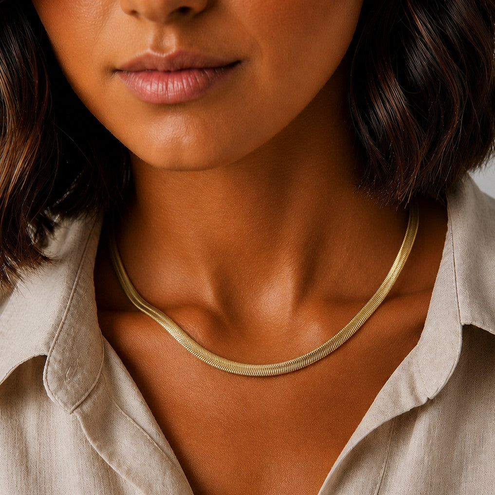 Goldfarbene Serena Schlangenkette, getragen von einem Model mit weißer Bluse und gebräunter Haut.