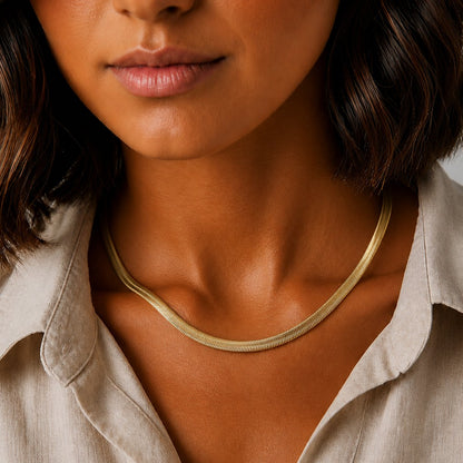 Goldfarbene Serena Schlangenkette, getragen von einem Model mit weißer Bluse und gebräunter Haut.
