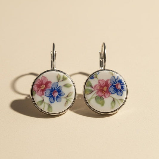 Handgefertigte runde Porzellanohrringe mit rosa und blauem Blumenmuster auf hellem beigem Hintergrund vom Edelatelier