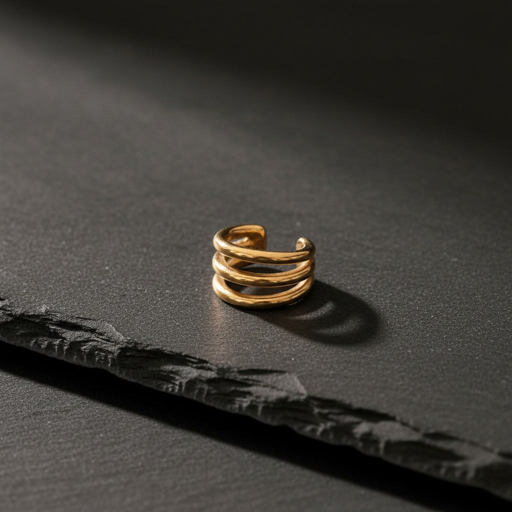 Intreccio Ear Cuff aus 18K vergoldetem Edelstahl auf schwarzem Hintergrund.