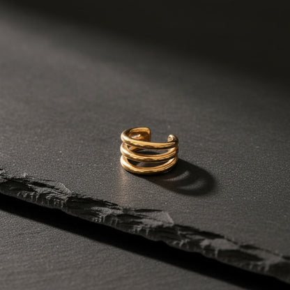 Intreccio Ear Cuff aus 18K vergoldetem Edelstahl auf schwarzem Hintergrund.