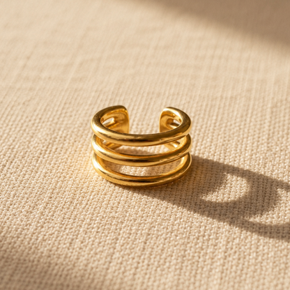 Goldener Intreccio Ear Cuff auf beigem Leinenstoff.